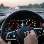 Comment comprendre une injection à contrôler sans paniquer ? Vue réaliste du tableau de bord d’une voiture avec un témoin d’alerte lié au système d’injection allumé, reflets discrets, et mains du conducteur attentives sur le volant, ambiance éditoriale automobile.