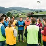 Groupe mixte de demandeurs d’emploi et de recruteurs portant des chasubles colorées, réunis pour un atelier collectif sur un terrain de football dans le Jura.